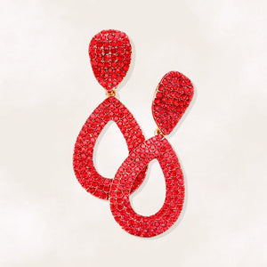 Red rhinestone pavé cut out teardrop pageant and formal earrings on gold on a beige background