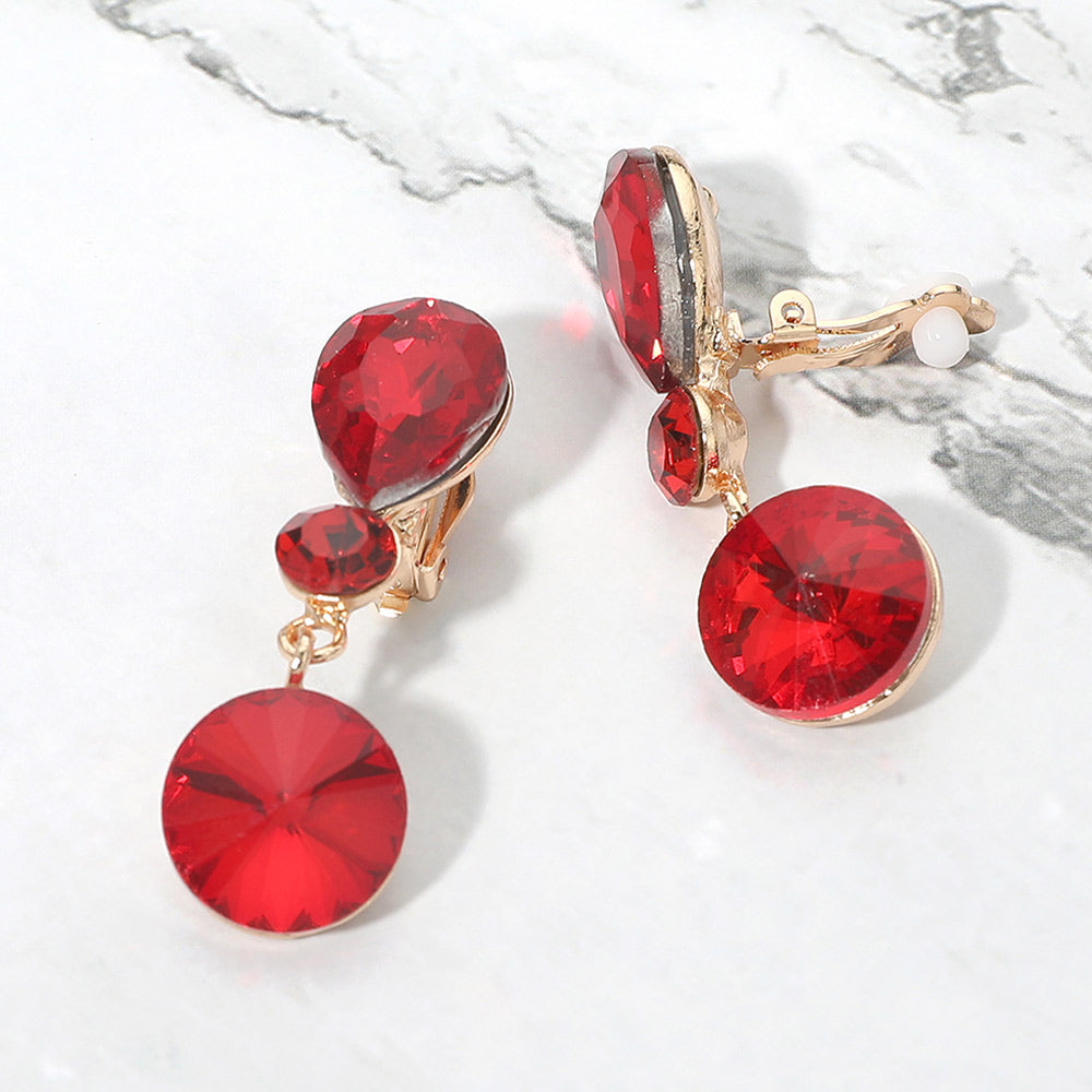 Red round crystal drop clip-on earrings on gold on white marble background