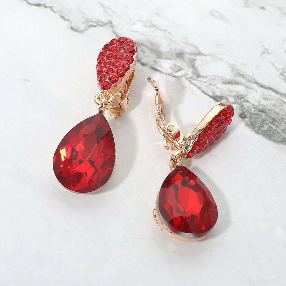 Red teardrop crystal drop clip-on earrings on gold on white marble background