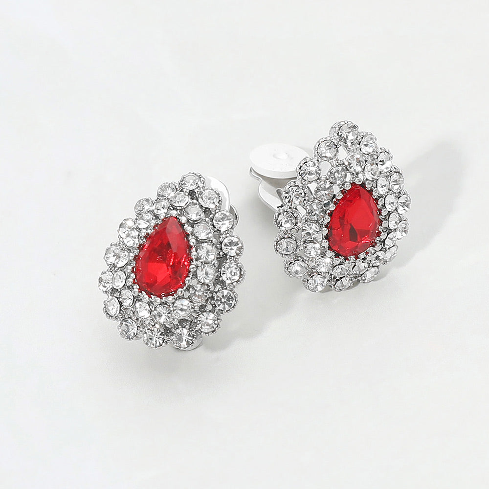 Red teardrop rhinestone halo clip-on earrings with silver-tone setting and classic crystal cluster design on a light gray background