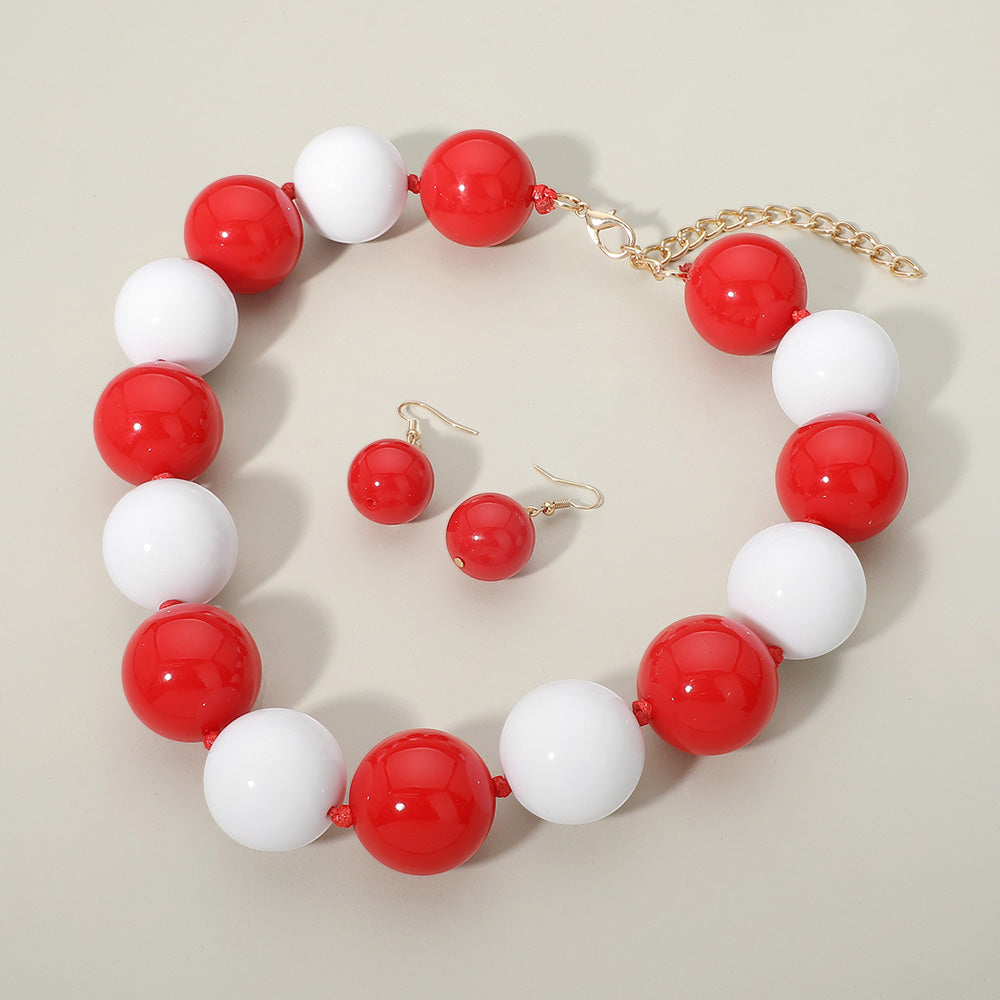 Red and white chunky ball beaded statement necklace set with oversized round beads and matching earrings, displayed on a beige background.