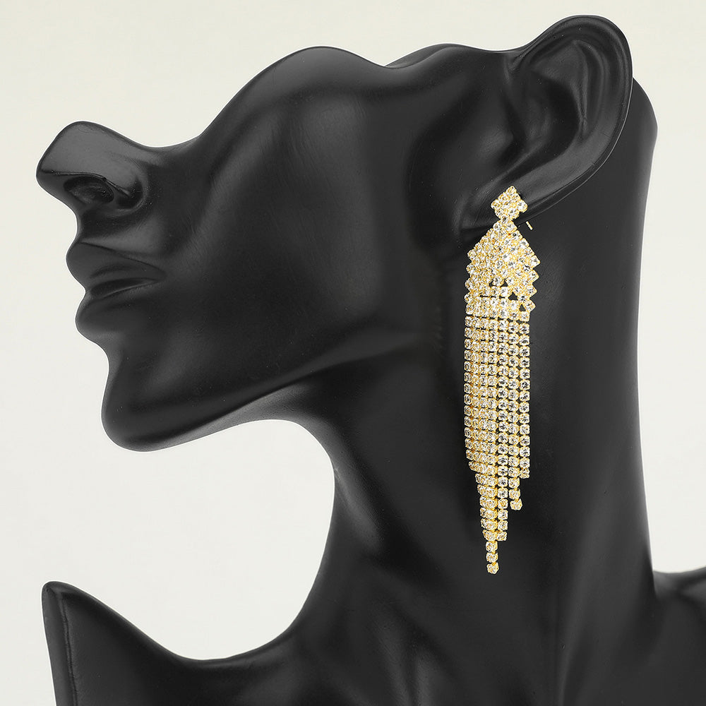 Long clear gold rhinestone fringe tassel earrings, gold backed, on a black mannequin ear — bold crystal statement jewelry for pageant, prom, weddings, and evening glam.