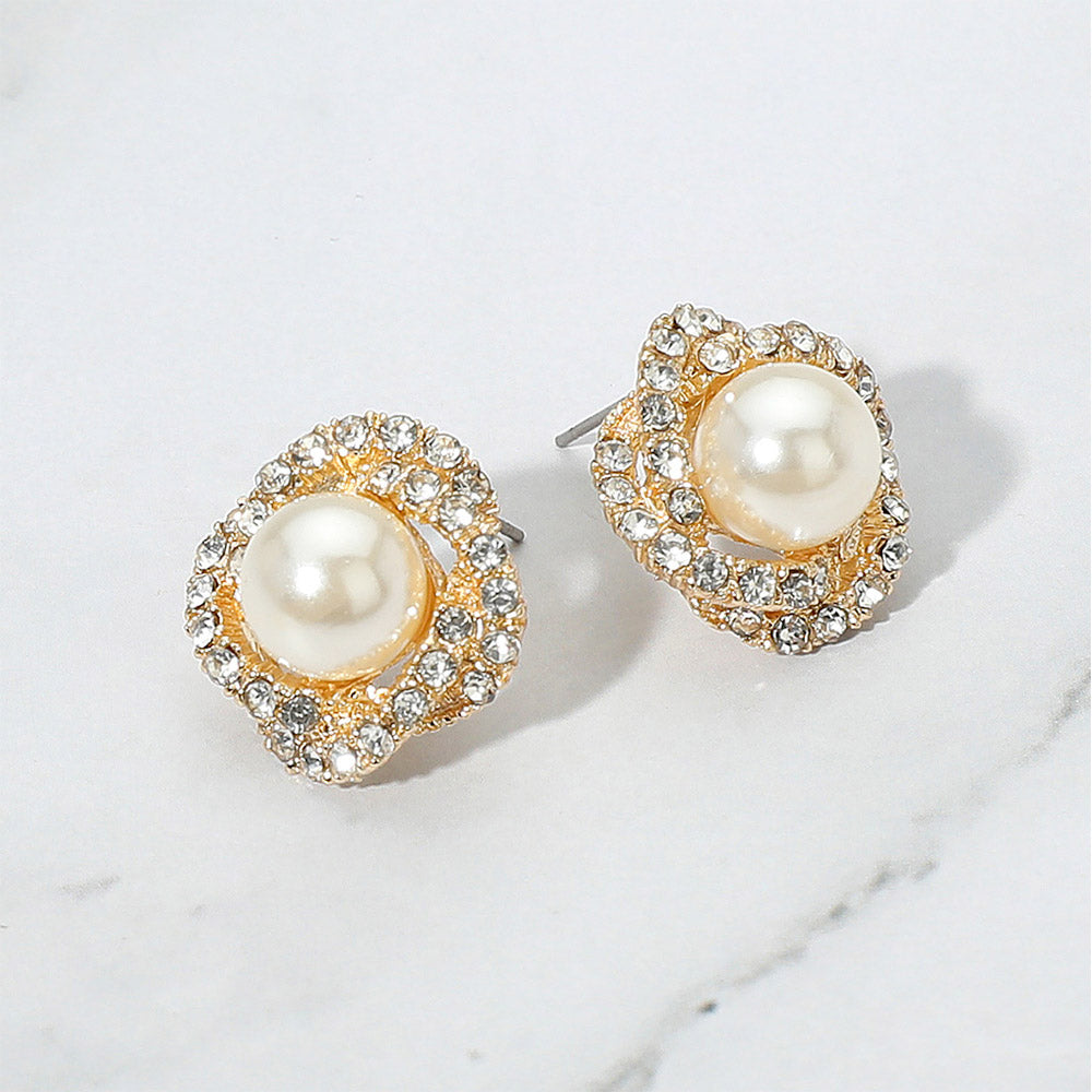 Cream pearl stud earrings with rhinestone trim on gold for weddings, proms, or pageants on a grey and white granite background