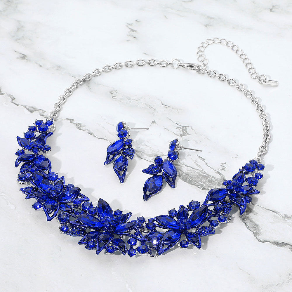 Royal blue sapphire collar-bib necklace set with earrings for pageants, homecoming, or formal wear on a grey and white granite background