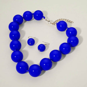 Royal Blue chunky ball beaded statement necklace set with oversized round beads and matching drop earrings, displayed on a light cream background.