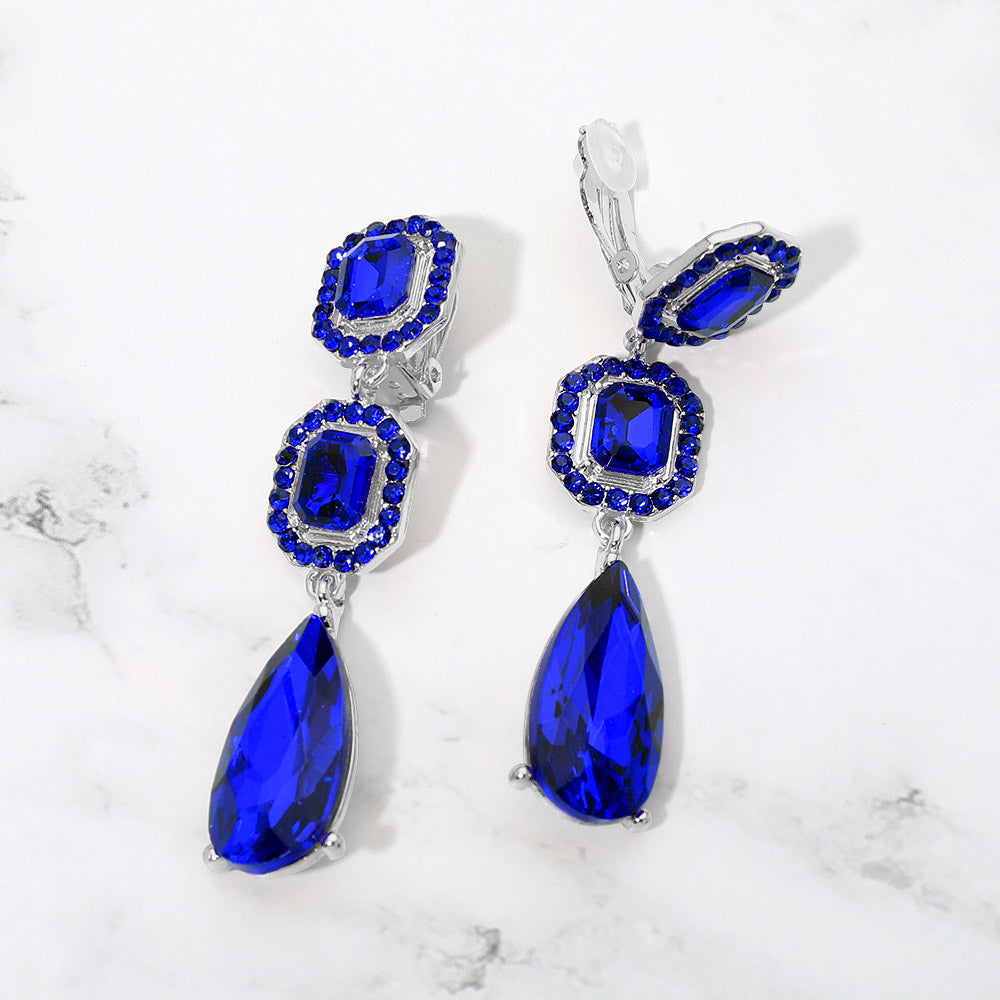 Sapphire royal blue crystal square and teardrop clip-on earrings on silver-tone metal, displayed against a white background.