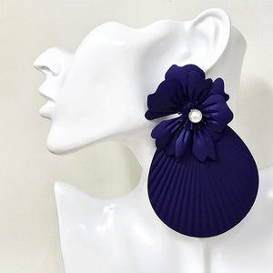 Oversized royal blue flower fan statement earrings with layered floral tops and large pleated fan drops, displayed on a white jewelry mannequin.