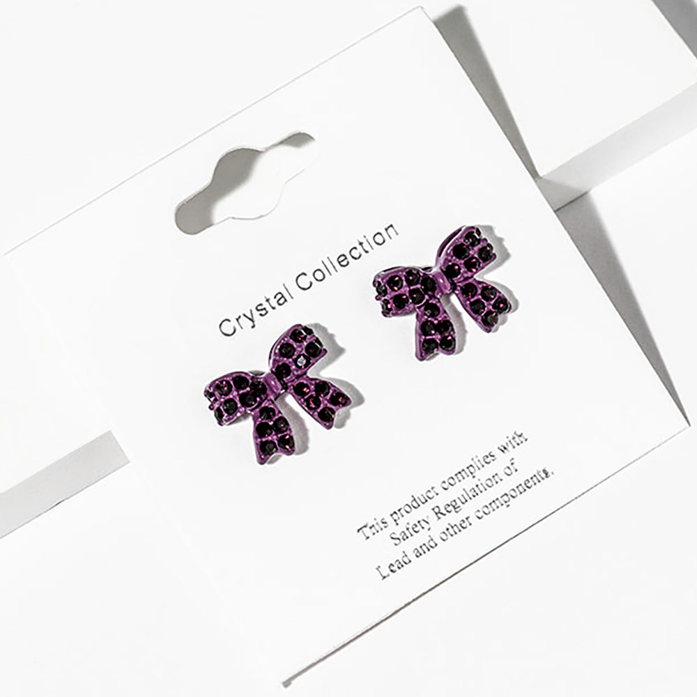 Purple bow-shaped stud earrings on a Crystal Collection card with safety information-for little girls’ pageant or everyday wear.
