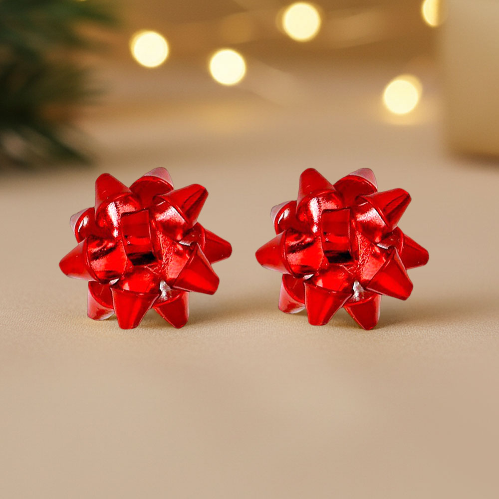 Red Christmas bow stud earrings in a dimensional gift-bow design, festive holiday jewelry for outfits and parties on a blurred out Christmas background.