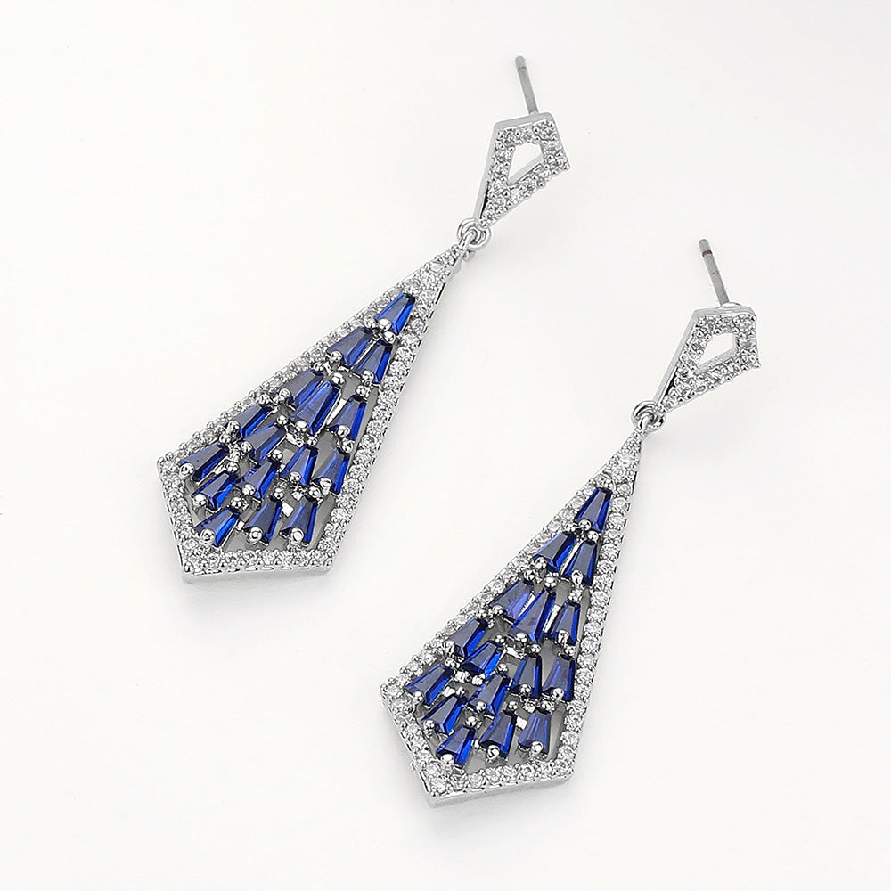 Sapphire Royal Blue crystal geometric baguette drop earrings in a silver finish featuring baguette-cut sapphire royal blue crystals arranged in an open geometric drop design, displayed on a beige stone background.