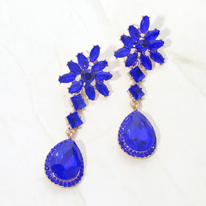 Sapphire royal blue crystal flower teardrop earrings in a gold finish featuring marquise crystal flower tops and large faceted royal blue teardrop drops, displayed on a white background.