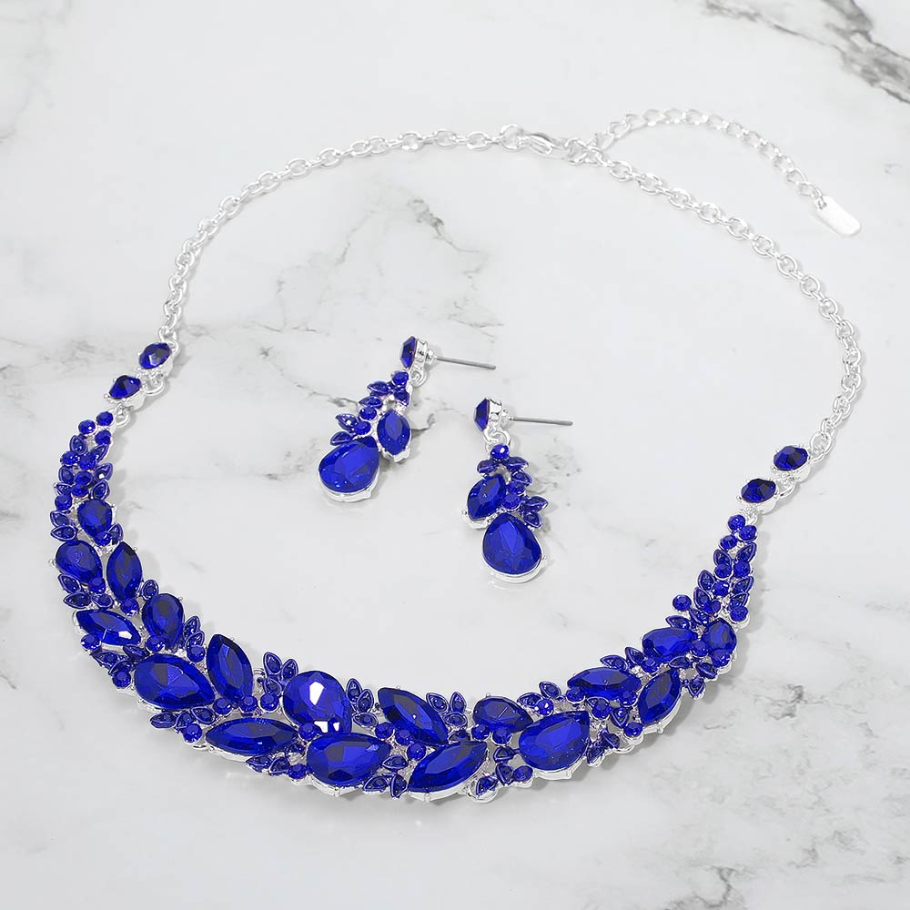 Sapphire royal blue marquise crystal cluster necklace set on silver with matching earrings, elegant statement jewelry for prom and evening wear on a marble background