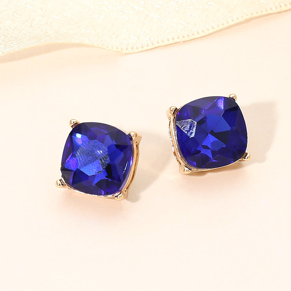 Sapphire royal blue square cushion stud earrings on gold on light beige background