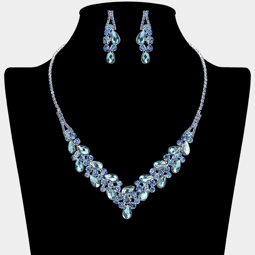 Light sapphire teardrop rhinestone necklace set with V-shaped crystal design and matching earrings, all backed in silver, for prom and formal wear. Shown on a black mannequin bust.  