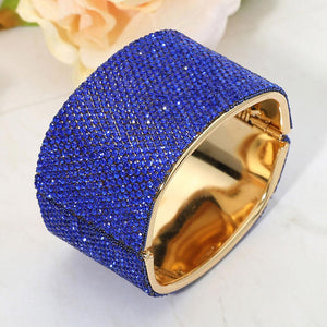 Sapphire wide rhinestone hinged bangle bracelet with a chunky statement silhouette and polished gold-tone setting
