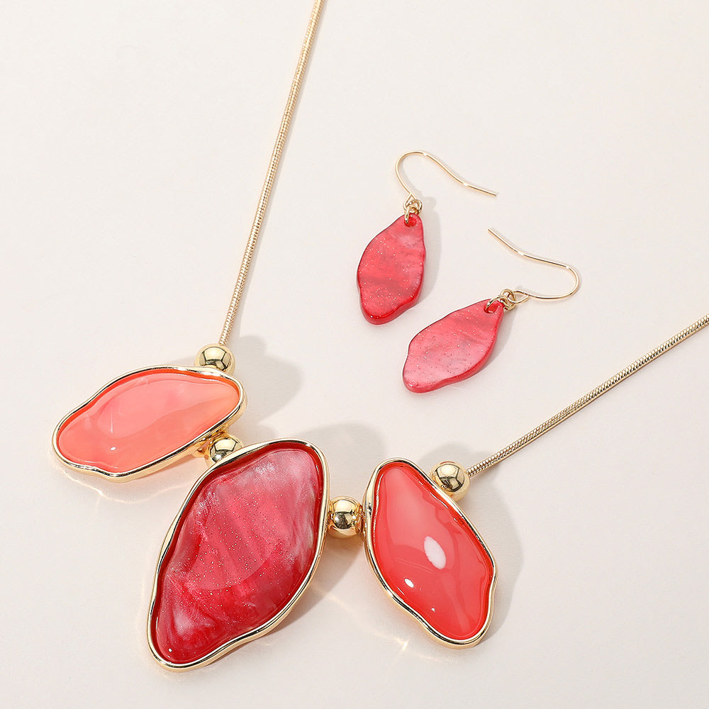 Shades of Red Abstract Sparkle necklace with organic-shaped pendants and matching drop earrings on a cream background