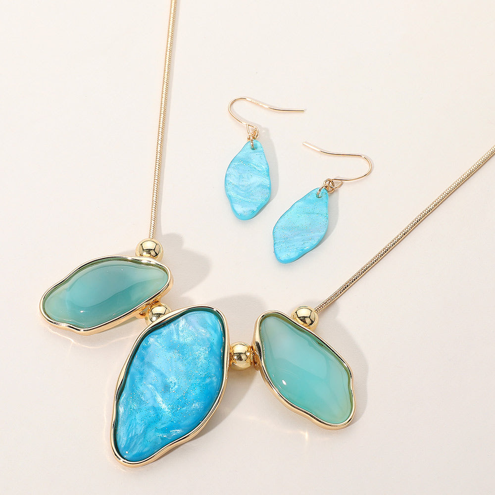 Shades of Turquoise Abstract Sparkle necklace with organic-shaped pendants and matching drop earrings on a cream background