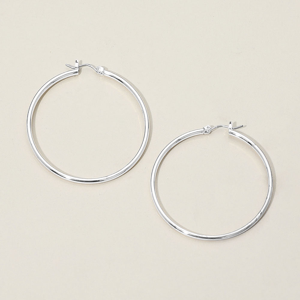 Silver classic hoop earrings with a 2-inch diameter displayed on a light grey background. 