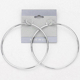 Silver hoop earrings with a 2.6-inch diameter and pin catch clasp, displayed on a light pink background.