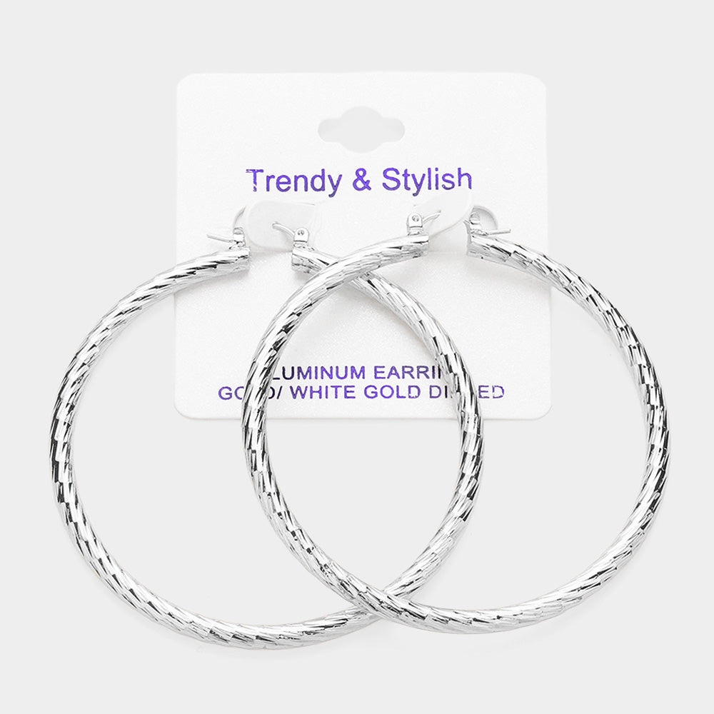Silver-tone textured 2.7-inch hoop earrings with a twisted design and pin catch closure, displayed on a white jewelry card against a light background.