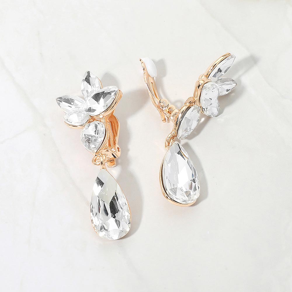 Slim clear crystal teardrop clip-on earrings on gold on white marble background