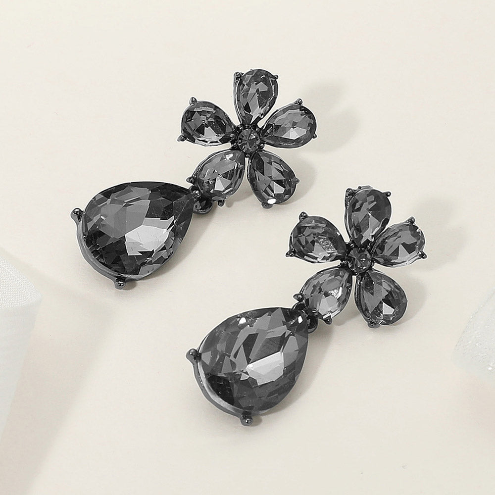 Black diamond flower and teardrop earrings with smoky rhinestones for pageant or prom on a cream background
