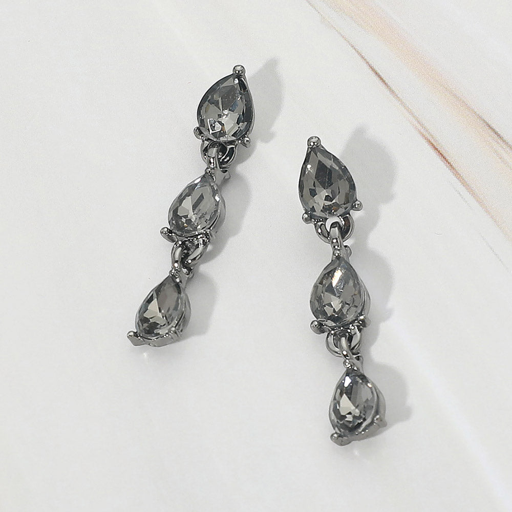 Small smoky grey triple teardrop cluster drop earrings backed in silver on a white marble background