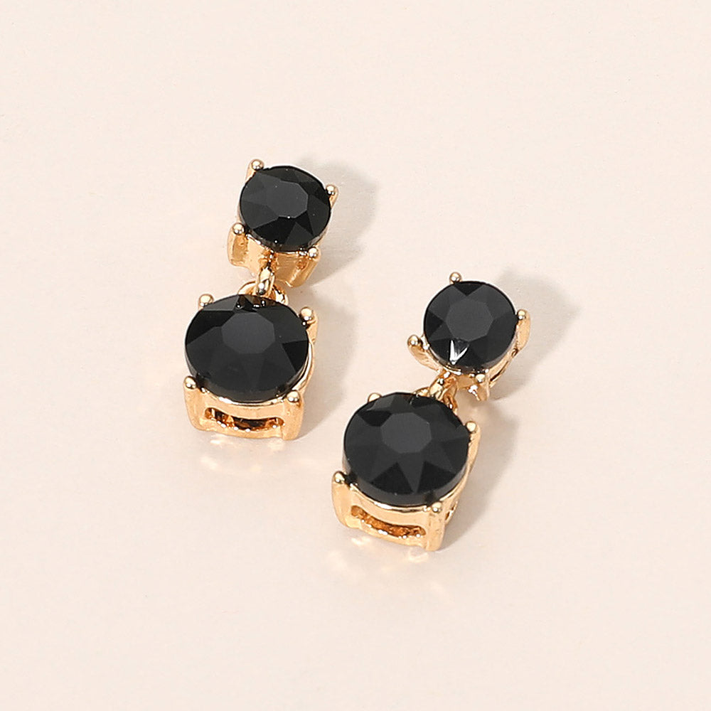 Small black double round little girls pageant drop earrings on gold on a beige background