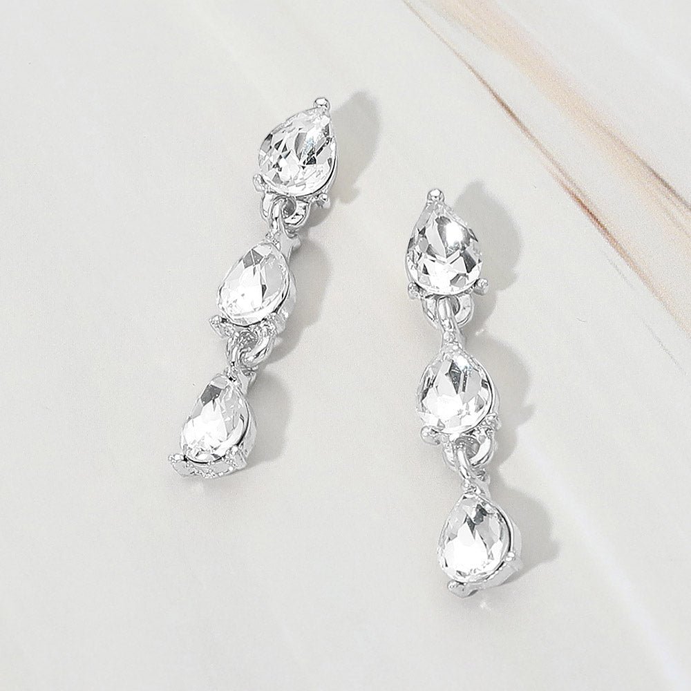 Small clear triple teardrop cluster drop earrings on silver on a white marble background