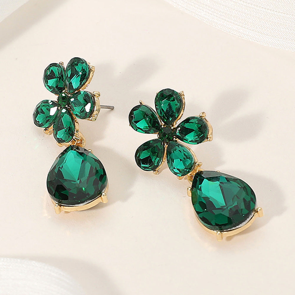 Emerald green rhinestone flower and teardrop earrings for prom or pageant stage on a cream background