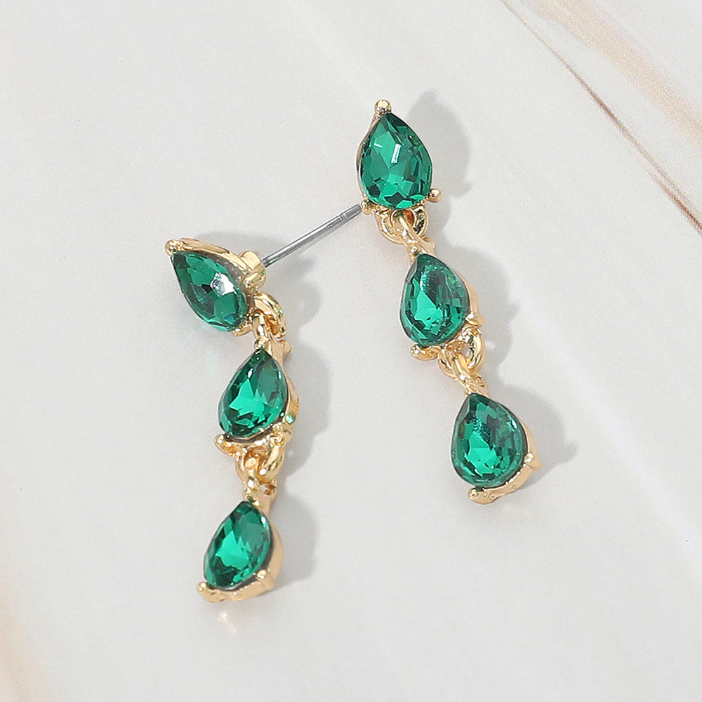 Small emerald green triple teardrop cluster drop earrings on gold on a white marble background