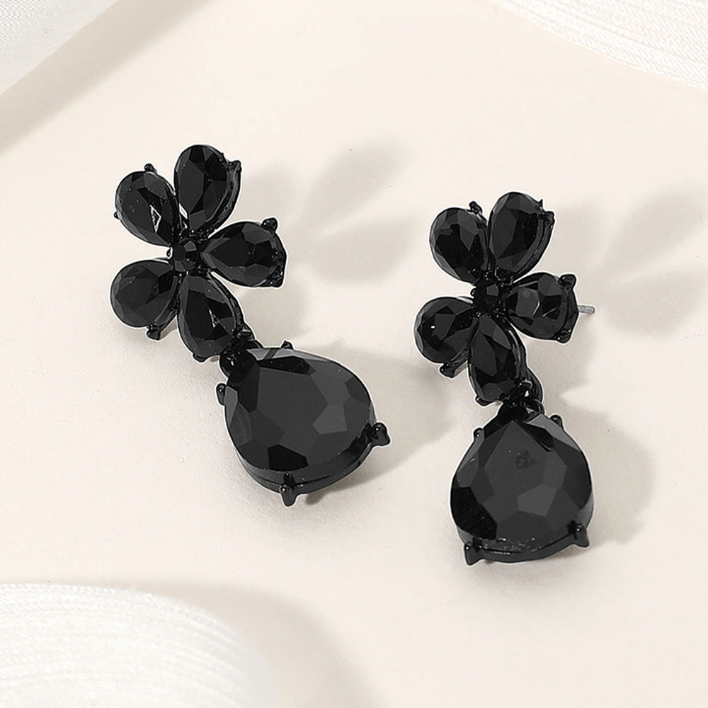 Jet black flower and teardrop rhinestone earrings for dramatic prom or pageant looks on a cream colored background