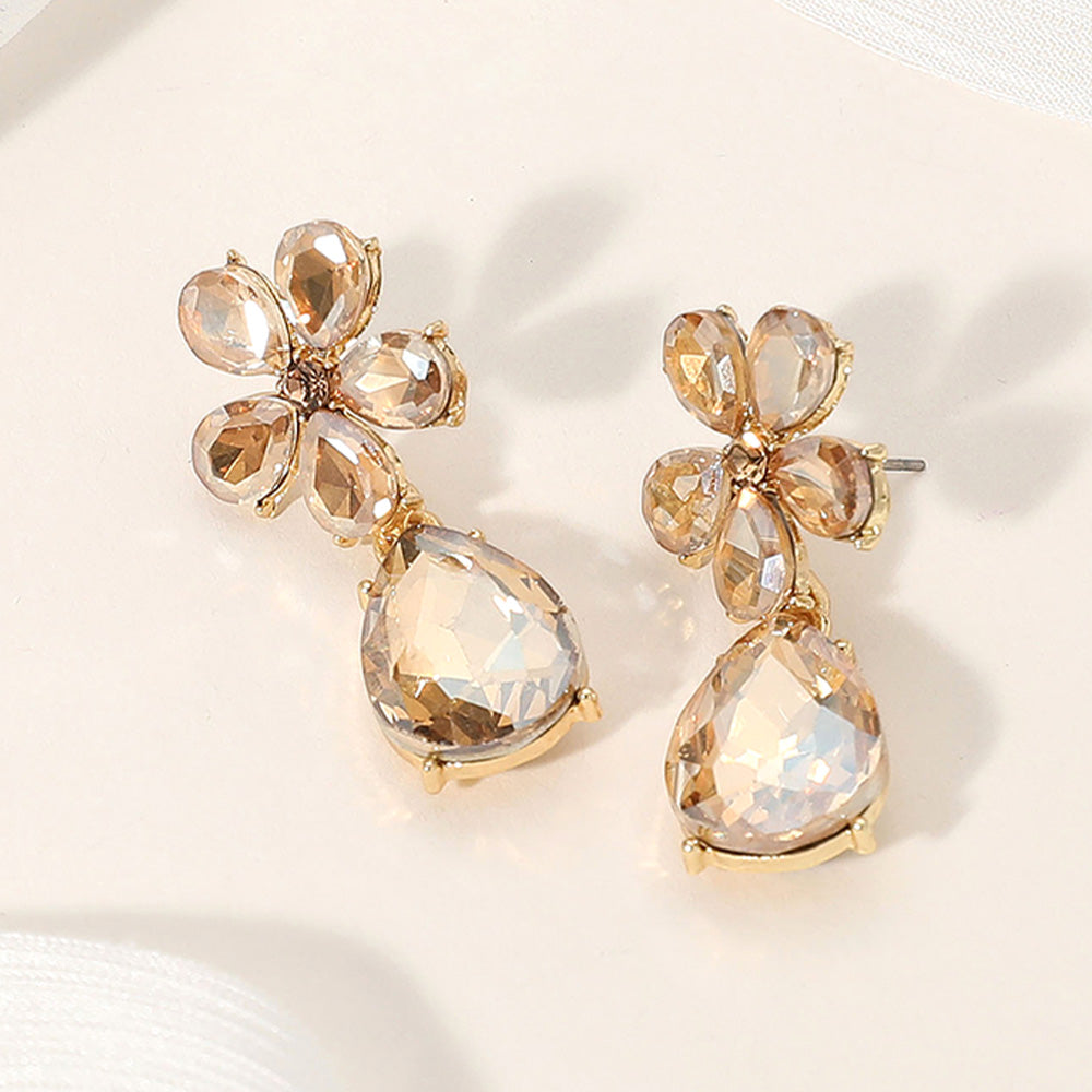 Light topaz flower and teardrop rhinestone earrings for golden pageant or evening style on a cream colored background