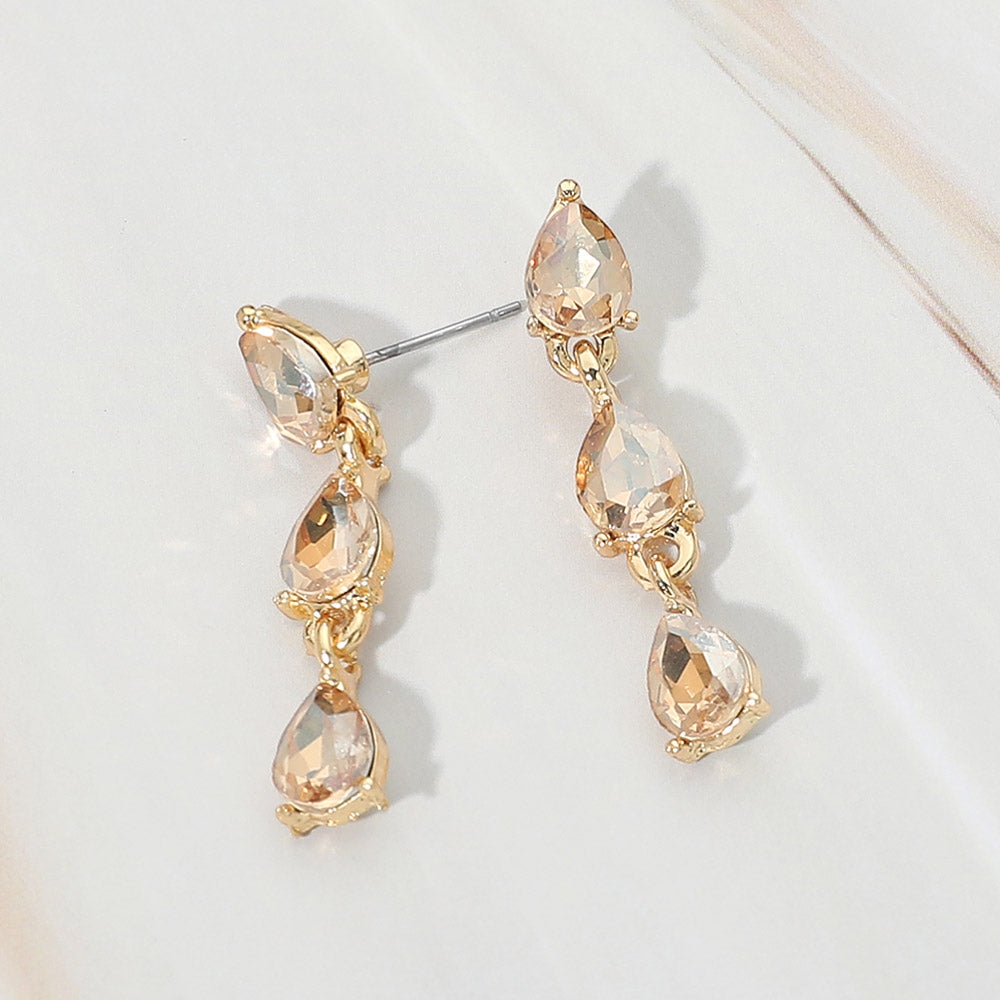 Small gold stone triple teardrop cluster drop earrings on gold on a white marble background