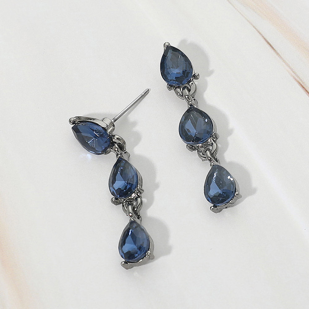 Small navy triple teardrop cluster drop earrings on black on a white marble background