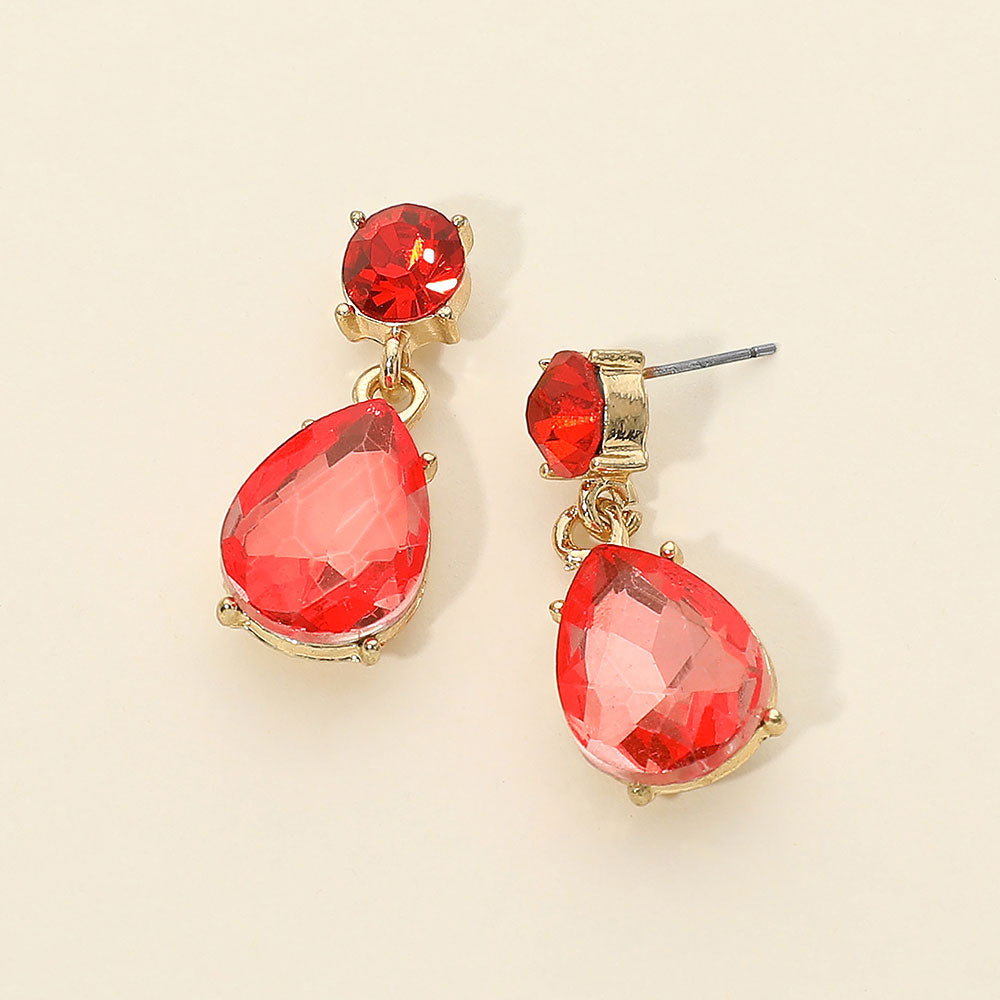 Orange crystal drop earrings on gold with a round top stone and large teardrop crystal, displayed on a light cream background.
