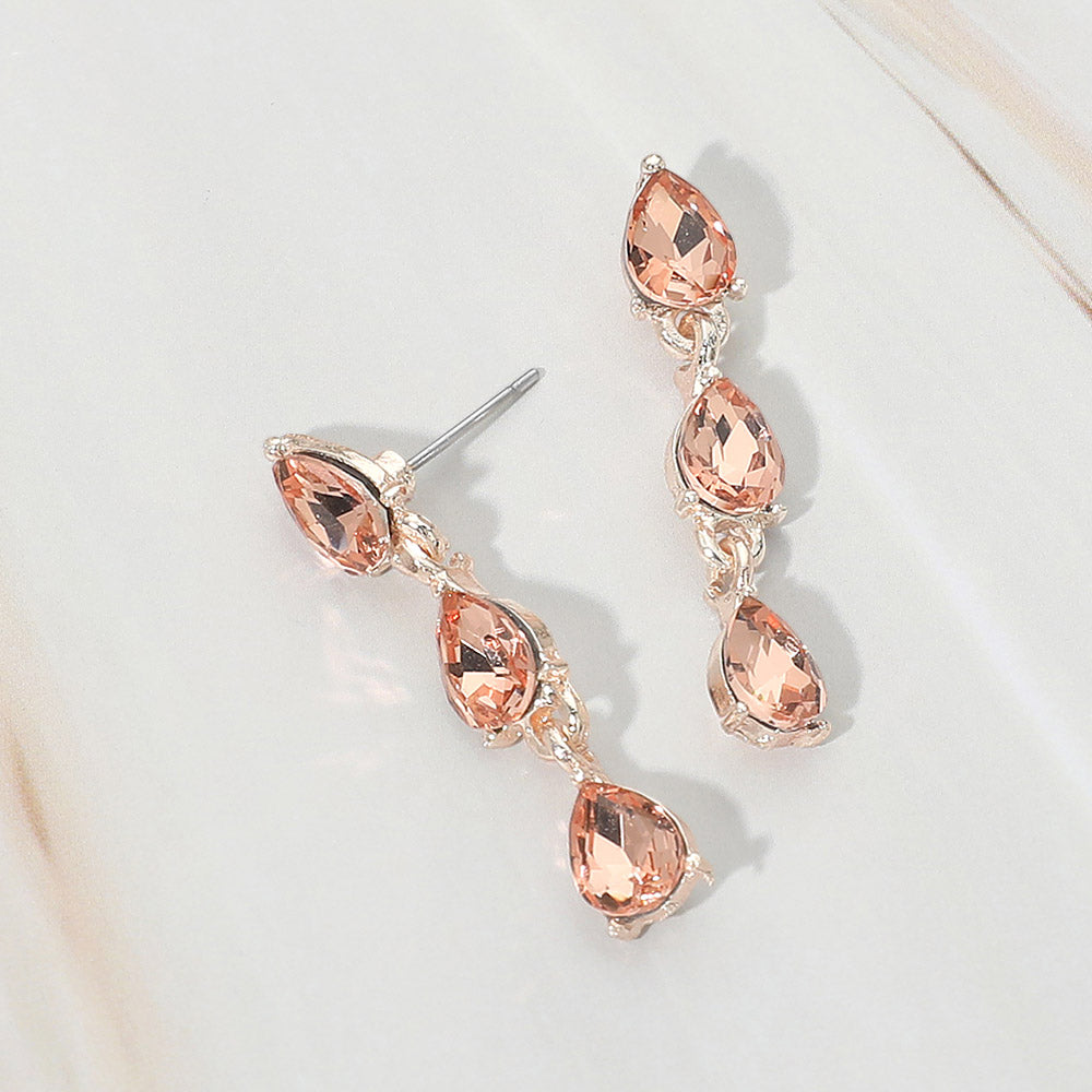 Small peach triple teardrop cluster drop earrings on rose gold on a white marble background