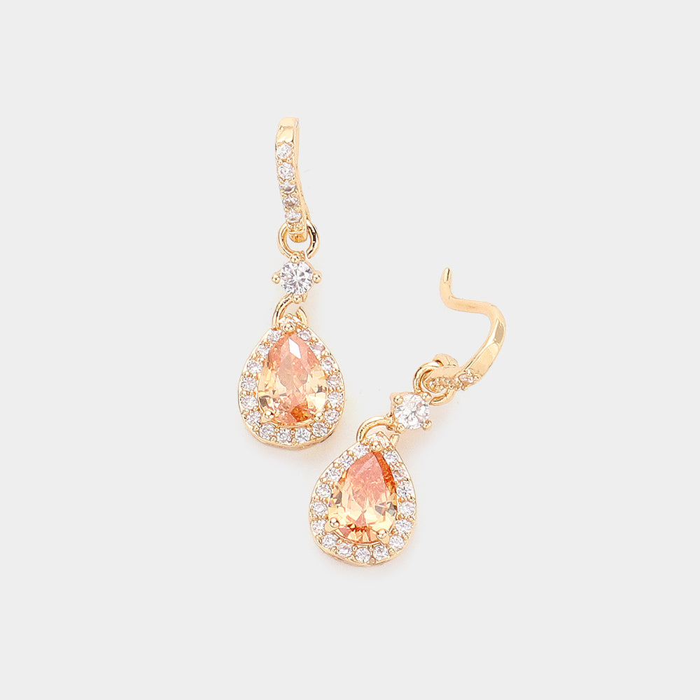 Gold earrings with peach-colored gemstones on a light gray background