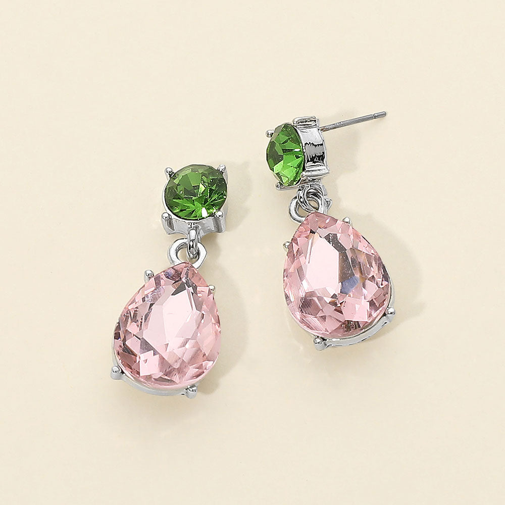 Pink and green crystal drop earrings on silver with a round top stone and large teardrop crystal, displayed on a light cream background.