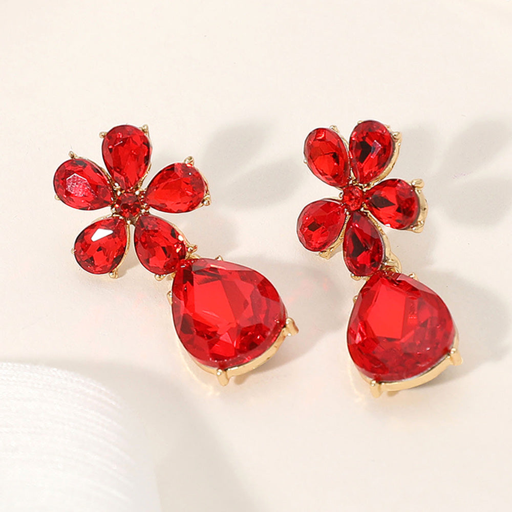 Red flower and teardrop rhinestone dangle earrings for bold pageant or prom style on a cream colored background