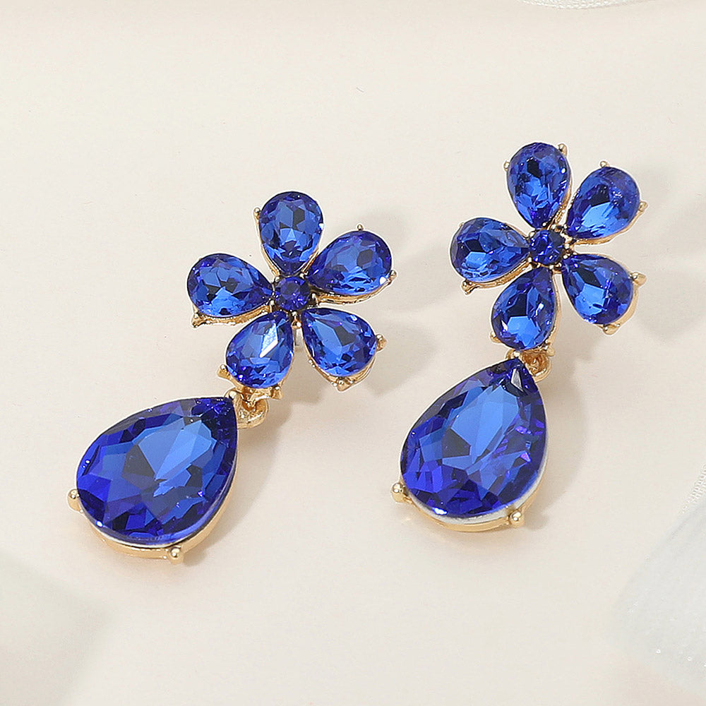 Sapphire flower and teardrop earrings with rhinestones for prom or pageant on a cream colored background