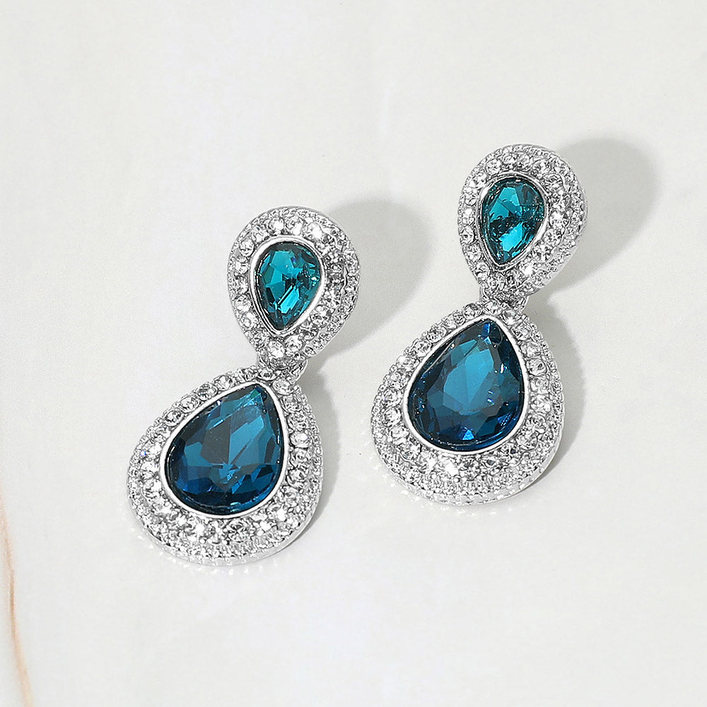 Small teal double teardrop crystal earrings on silver with rhinestones on white background