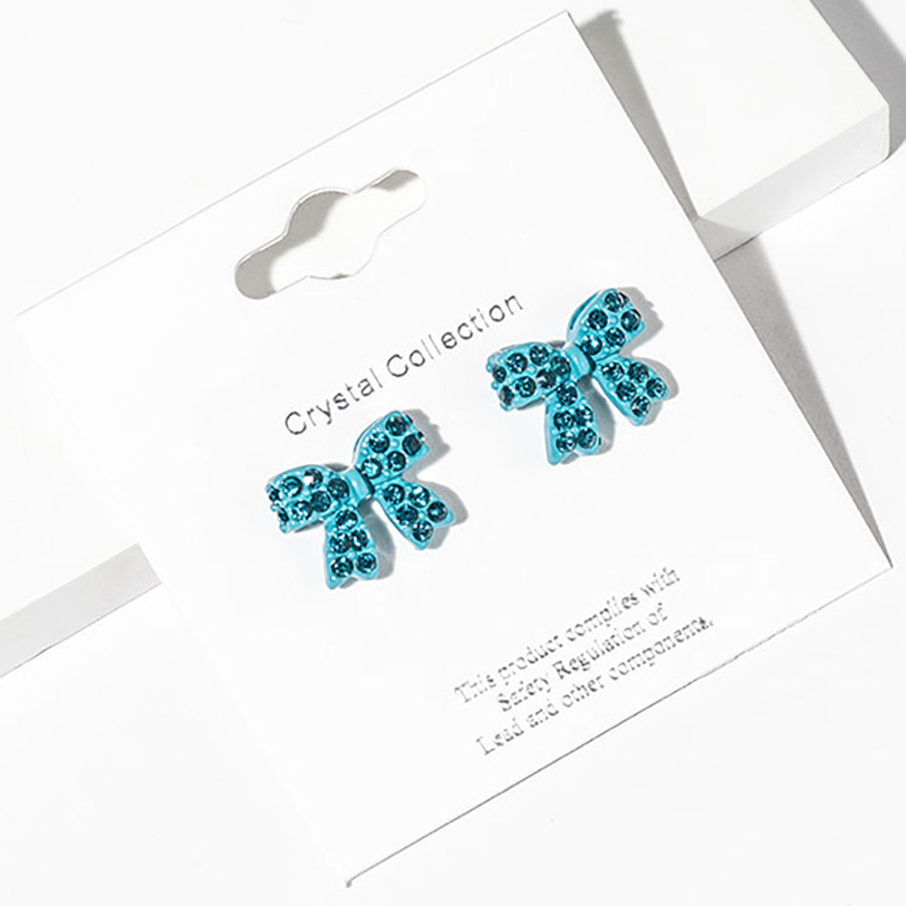 Teal bow-shaped stud earrings on a Crystal Collection card with safety information-for little girls’ pageant or everyday wear.
