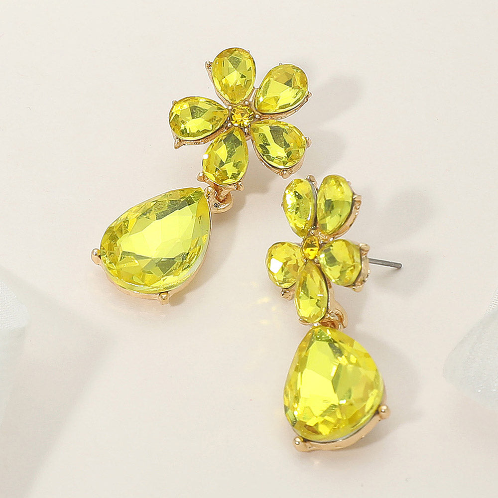 Yellow rhinestone flower and teardrop earrings for bright pageant or prom looks on a cream background