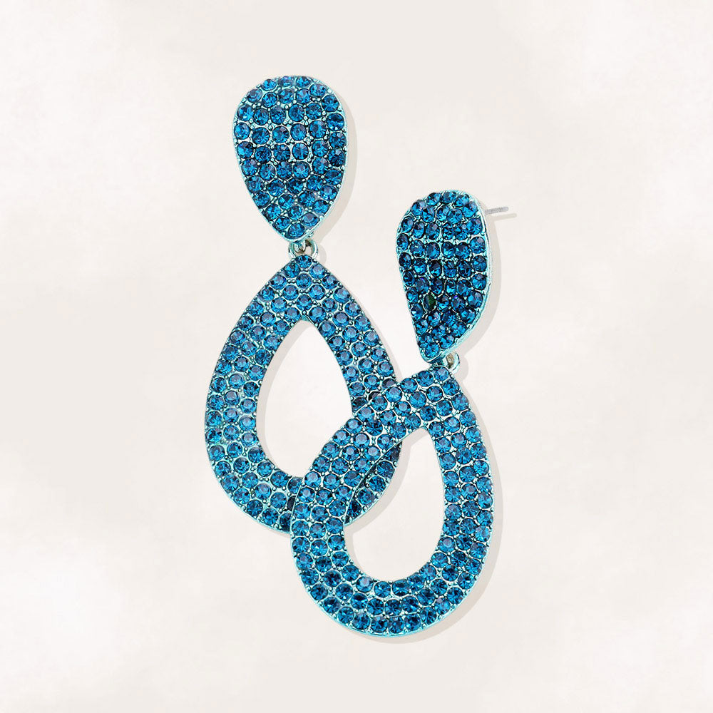 Teal rhinestone pavé cut out teardrop pageant and formal earrings on silver on a beige background