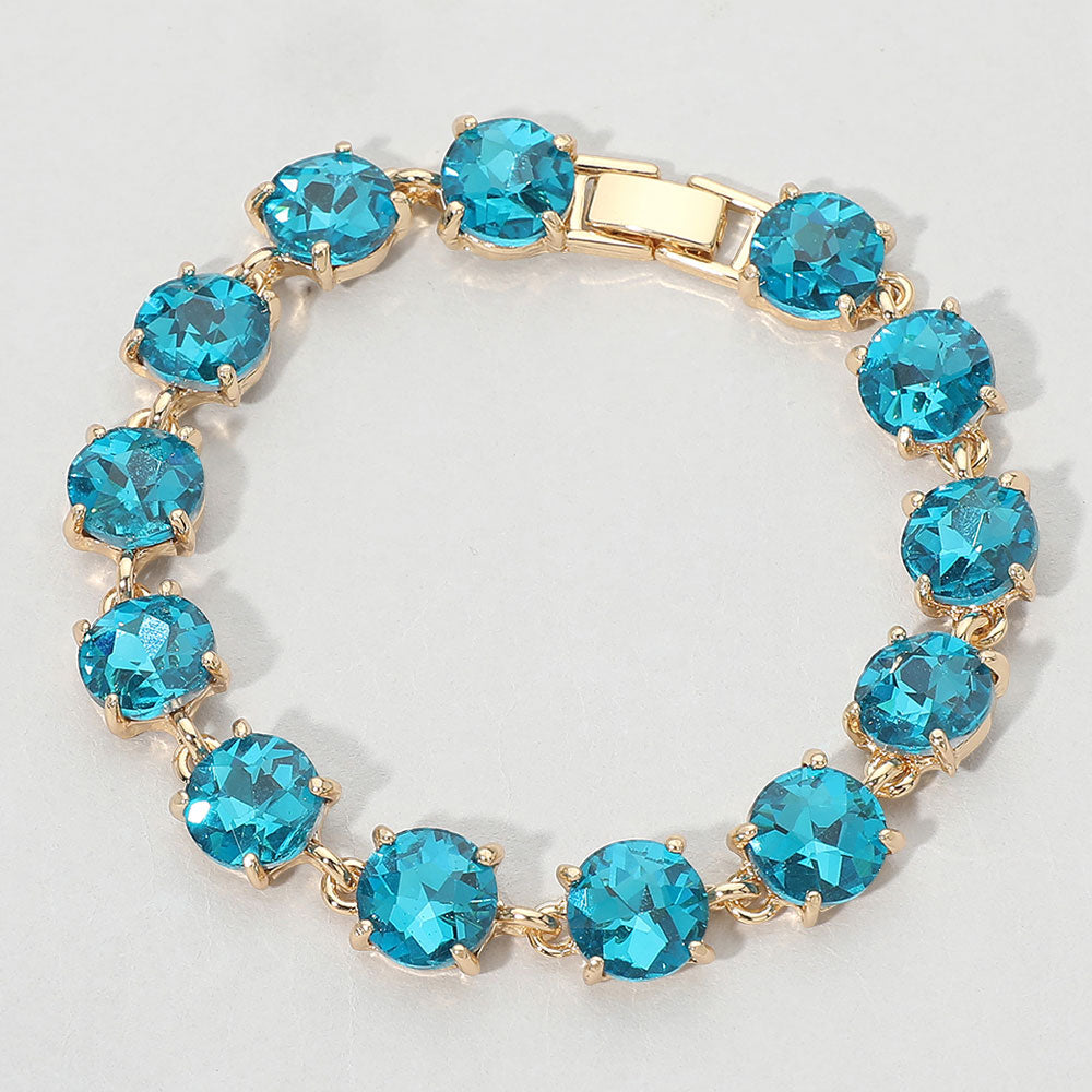 Gold bracelet with blue gemstones on a light gray background