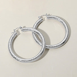 Textured silver metal hoop pin catch earrings on a white background