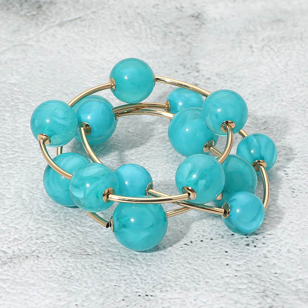 Turquoise chunky ball 3-piece stretch bracelet set on gold displayed on a light textured background.