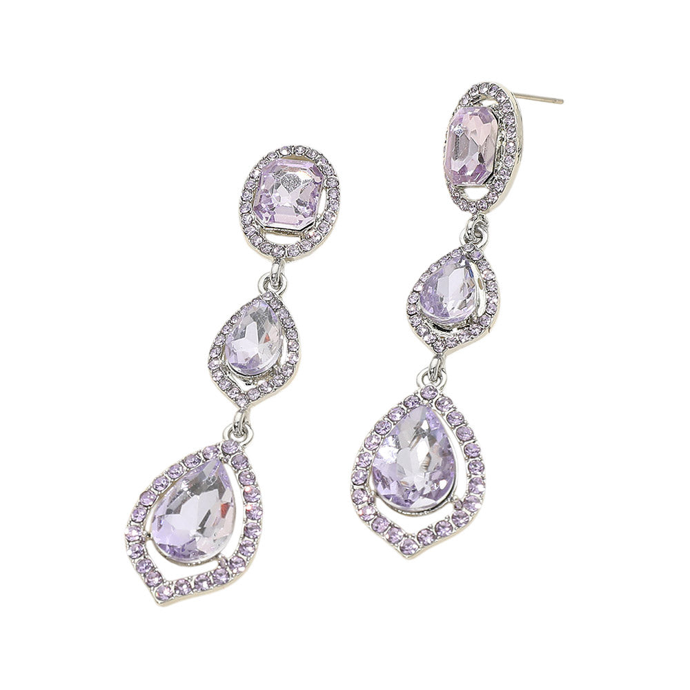 Pair of silver-tone drop earrings featuring large violet purple oval and pear-shaped crystals surrounded by small clear stones on a light gray background.