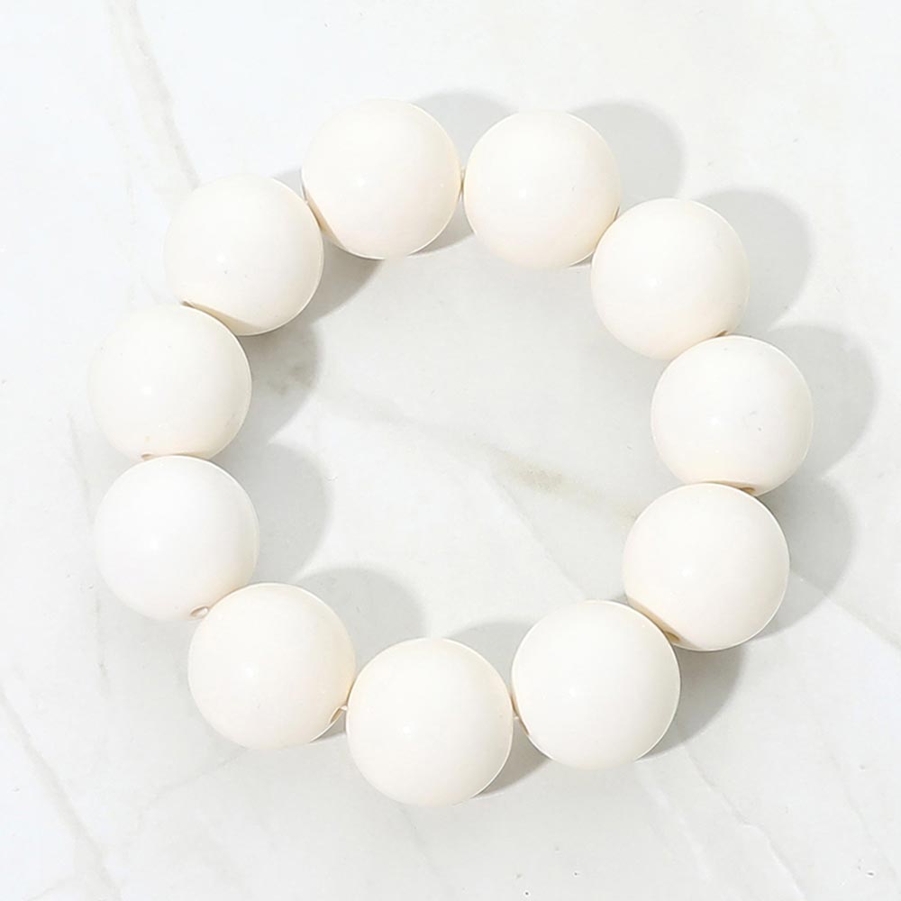 White chunky ball beaded stretch bracelet with oversized round beads, displayed on a white marble background.